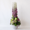 Tall delphinium arrangement with greenery in a grey pot
